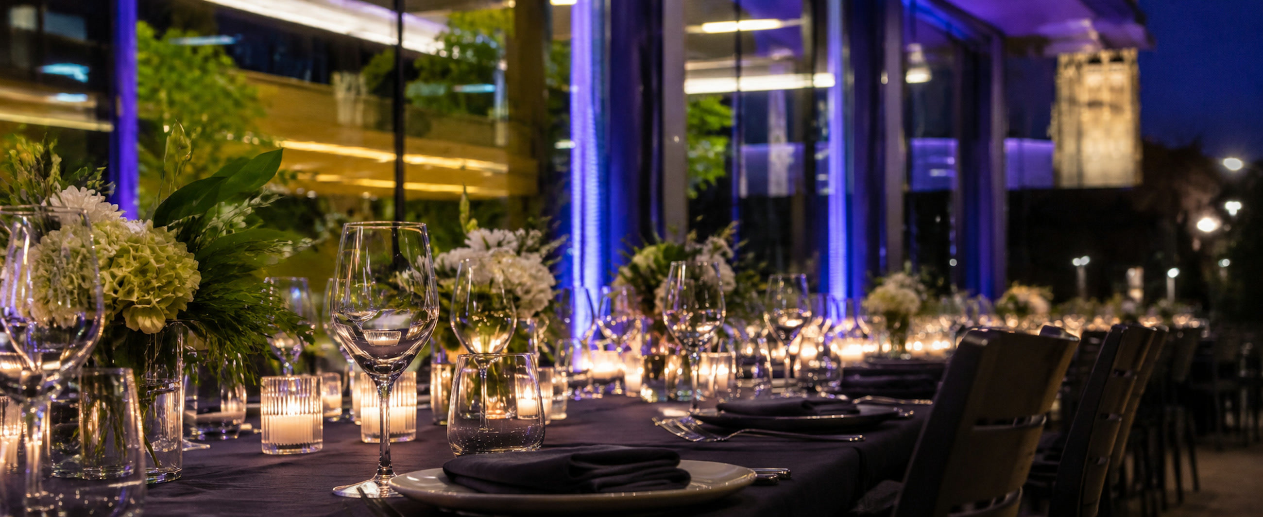 Elegant candlelit outdoor dinner at Penn Pavilion, Duke University, with purple uplighting and Duke Chapel in the background